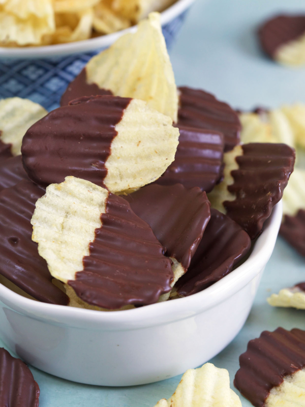 A white bowl is filled to the brim with chocolate covered potato chips.