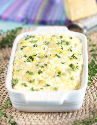 Creamed Corn in a white dish with thyme sprinkled on top.