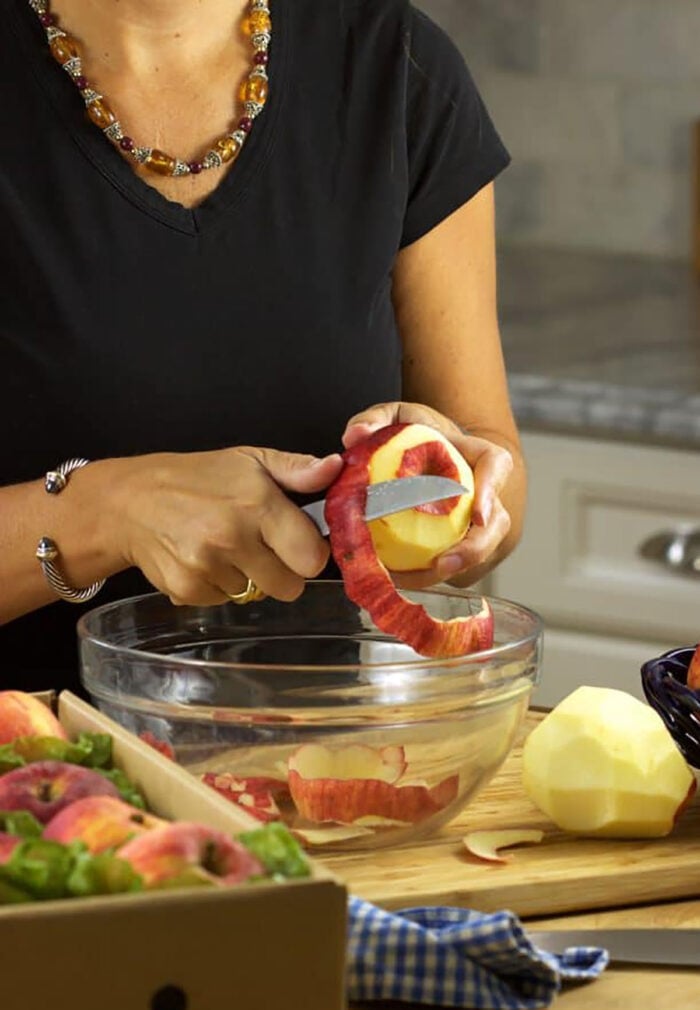 apple being peeled over a glass bowl