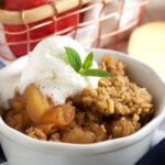 Crock Pot apple crisp in a white ramekin with whipped cream on top