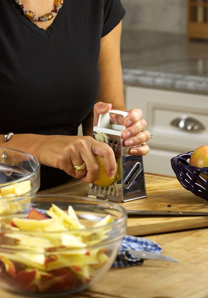 apple being grated in a bowl.