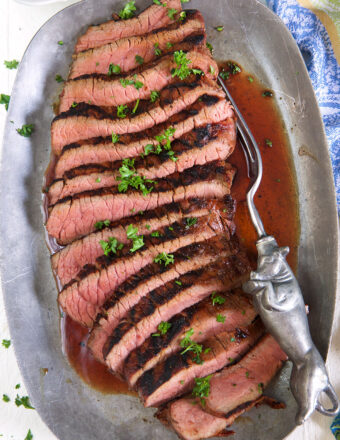 Sliced red meat is presented on a silver platter.