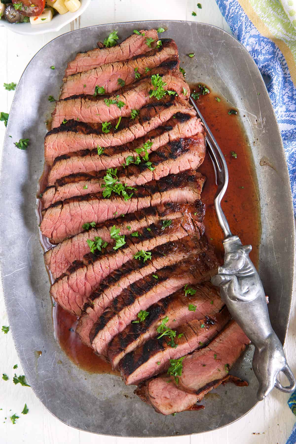 Sliced red meat is presented on a silver platter. 