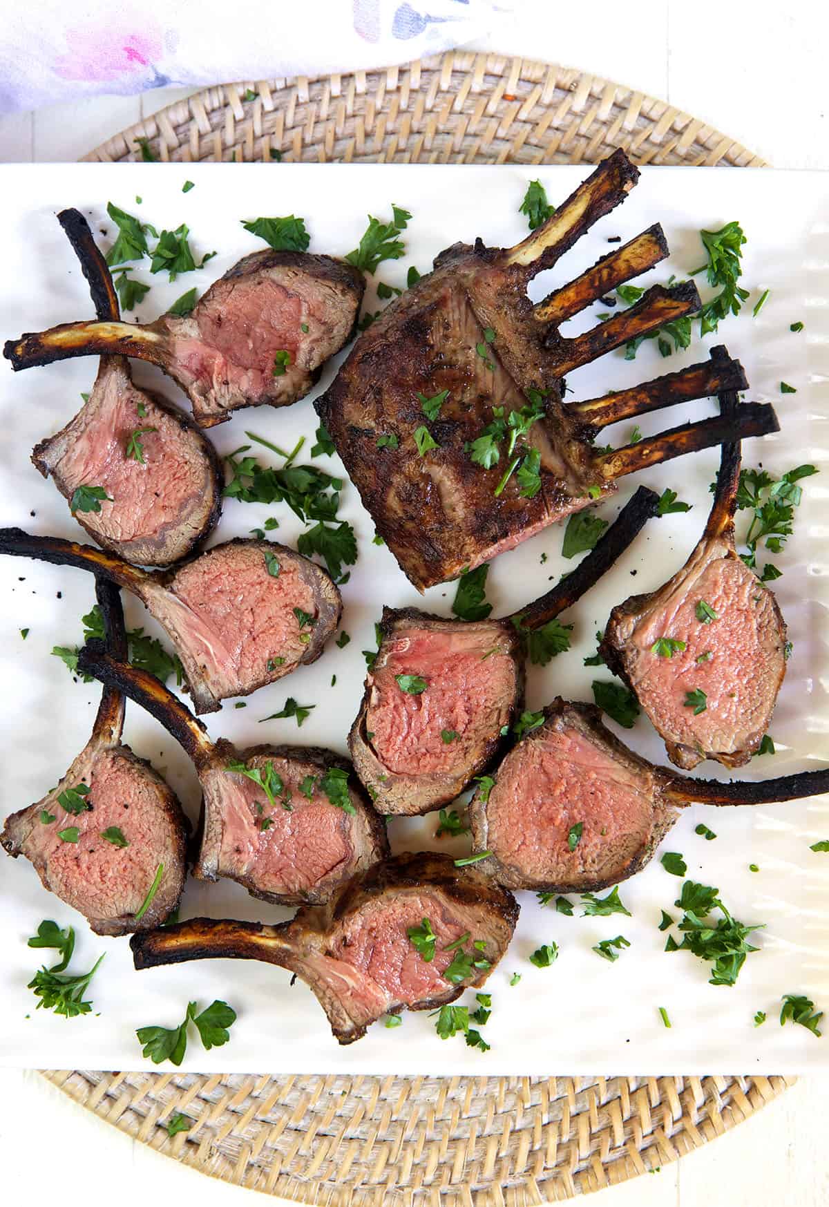 Several pieces of grilled lamb are presented on a white platter, ready to be eaten. 