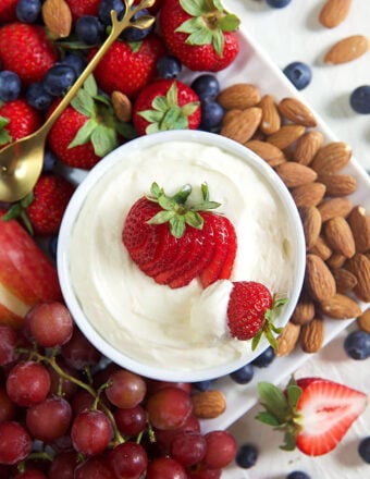 fruit platter with a bowl of marshmallow fruit dip with a strawberry on top.