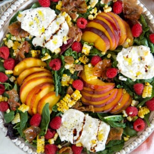 A peach salad in a large serving bowl is drizzled with hot honey.