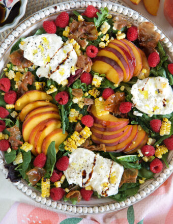 A peach salad in a large serving bowl is drizzled with hot honey.