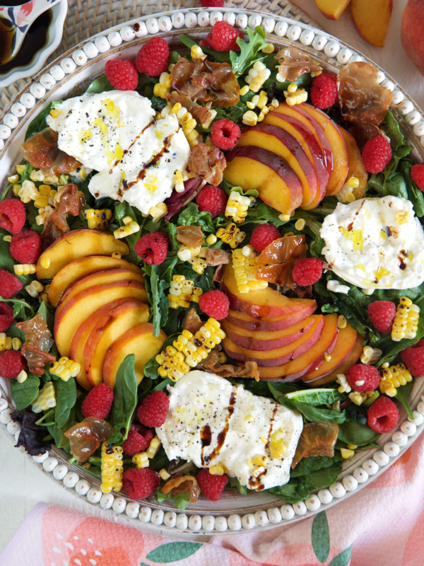 A peach salad in a large serving bowl is drizzled with hot honey.