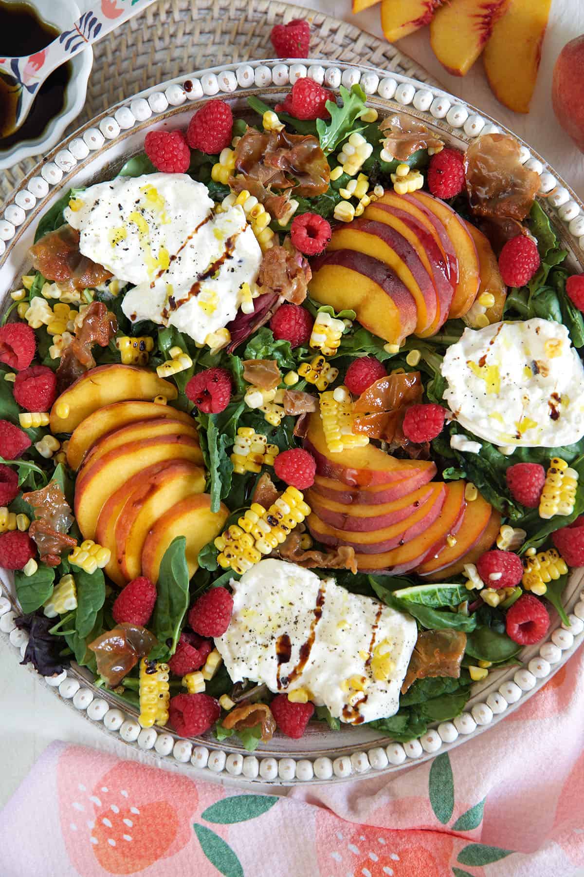 A peach salad in a large serving bowl is drizzled with hot honey. 