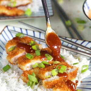 Sliced pork Katsu on a bed of rice with sauce being drizzled on top