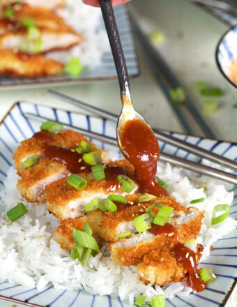 Sliced pork Katsu on a bed of rice with sauce being drizzled on top