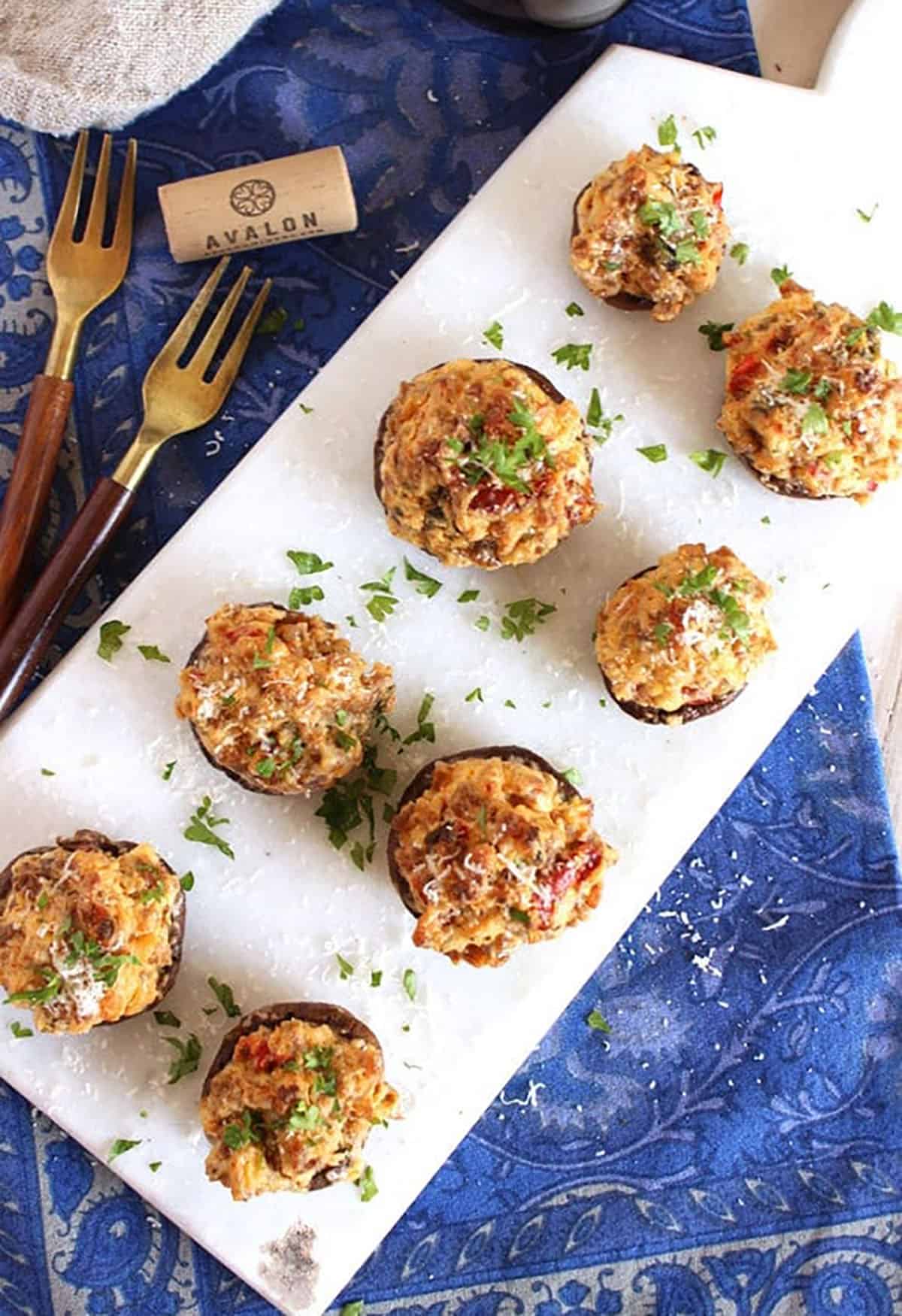 Sausage Stuffed Mushrooms arranges on a white marble serving board.
