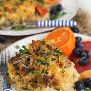 Tater tot breakfast casserole on a white plate with fruit.