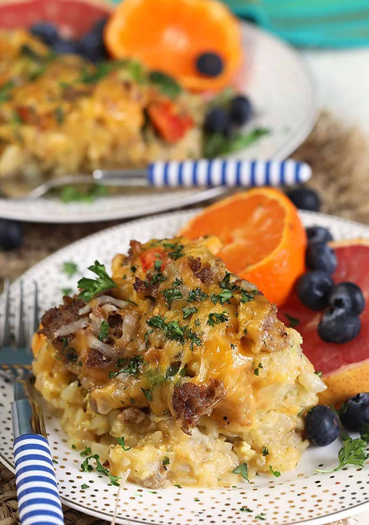 Tater tot breakfast casserole on a white plate with fruit.