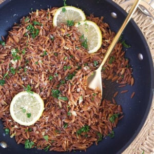 Cooked orzo is topped with fresh parsley in a skillet.