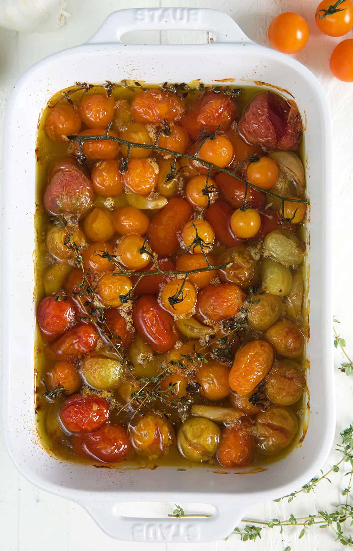 Tomatoes baked in oil are presented in a large white casserole dish. 