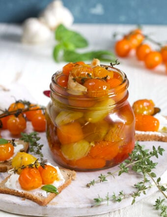 A jar of tomato confit is on a white surface.