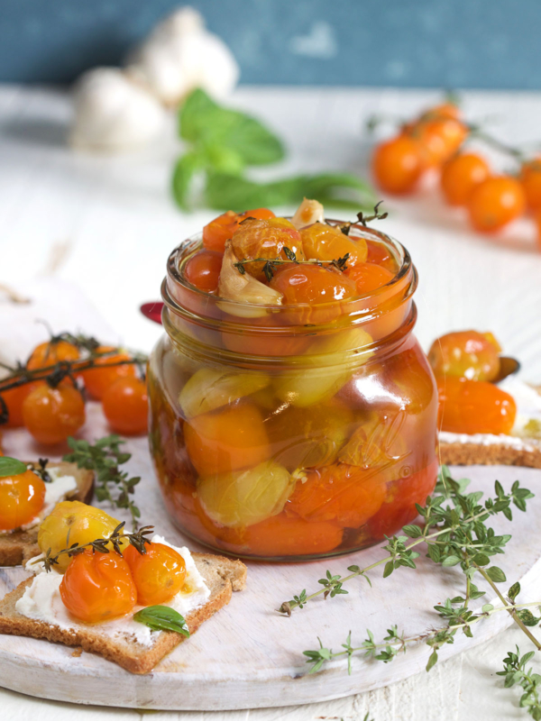 A jar of tomato confit is on a white surface.
