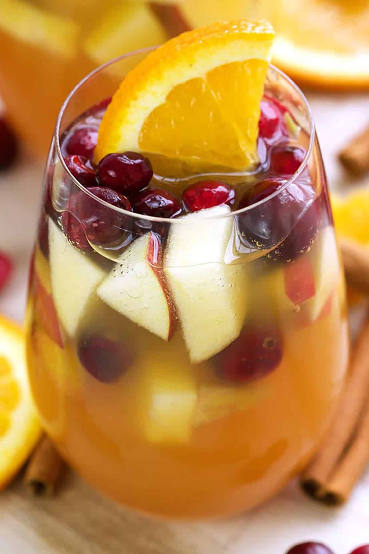 Wine glass filled with apple cider sangria and garnished with an orange wedge