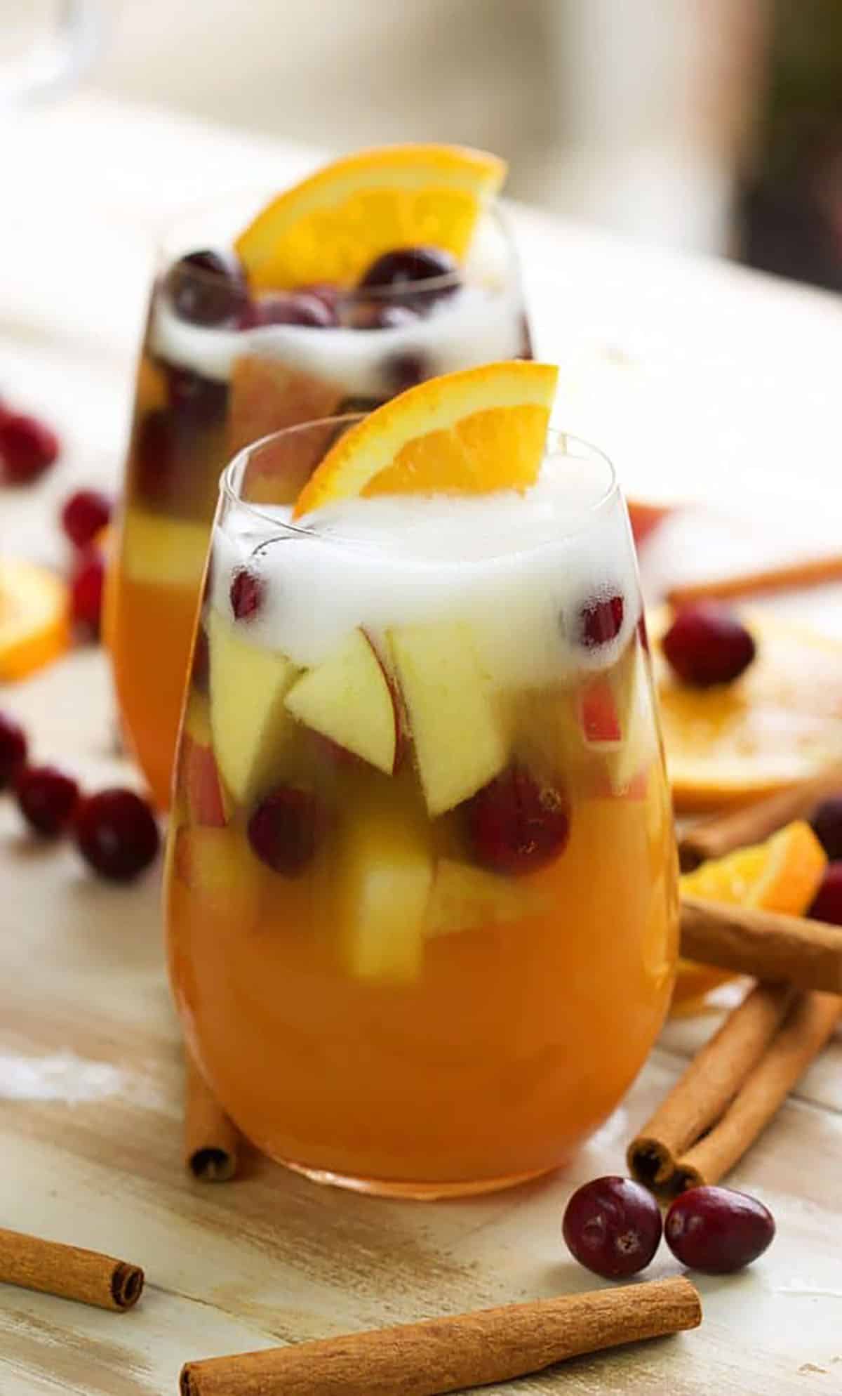 Apple Cider Sangria in a wine glass with foam on top from champagne.