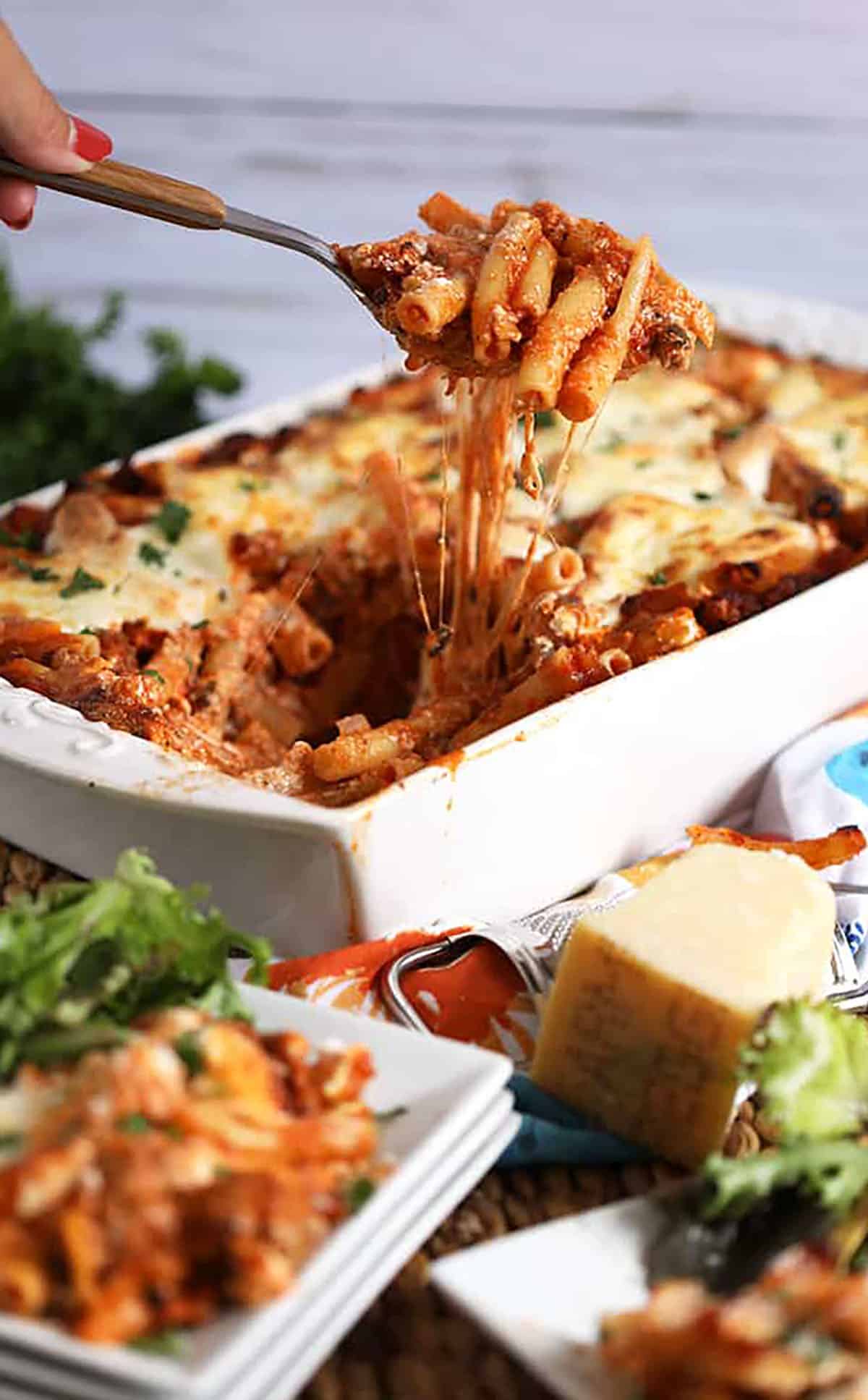 Easy Baked Ziti recipe in a white casserole with a spoonful of ziti with stretchy cheese