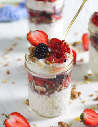 A golden spoon is placed in a berry yogurt parfait.