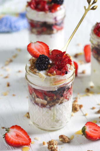A golden spoon is placed in a berry yogurt parfait.