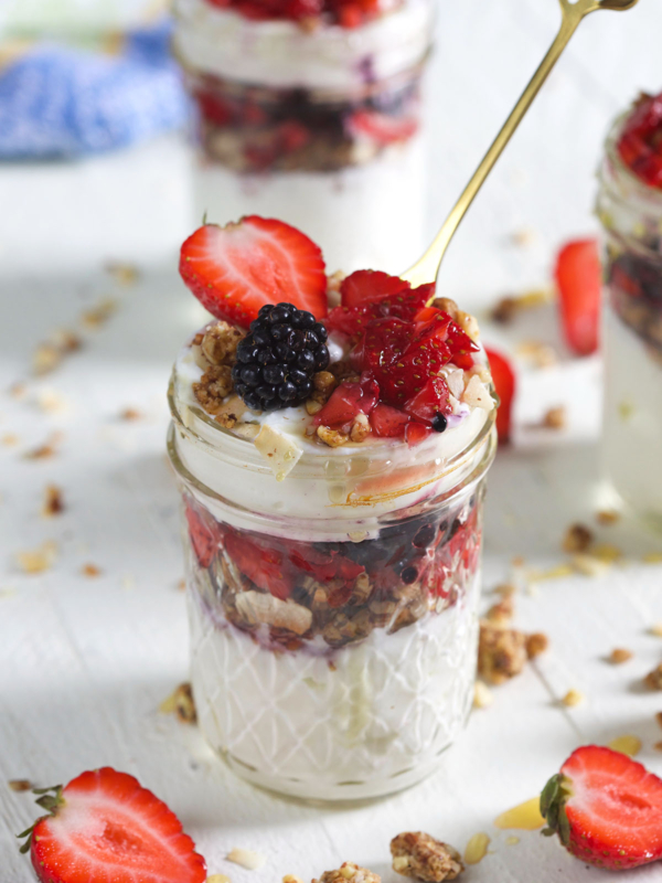 A golden spoon is placed in a berry yogurt parfait.
