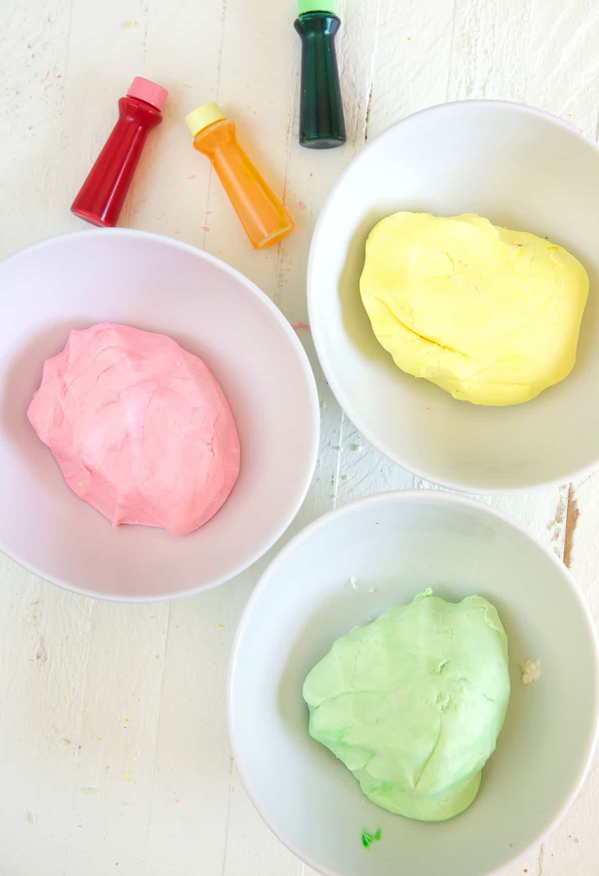 Three small bowls contain pink, yellow, and green dough for butter mints.