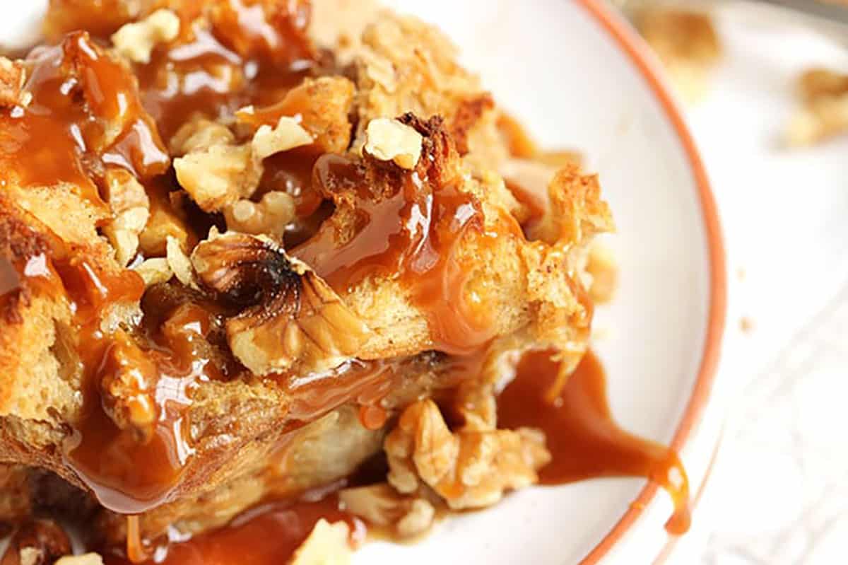 corner of apple bread pudding on a white plate.