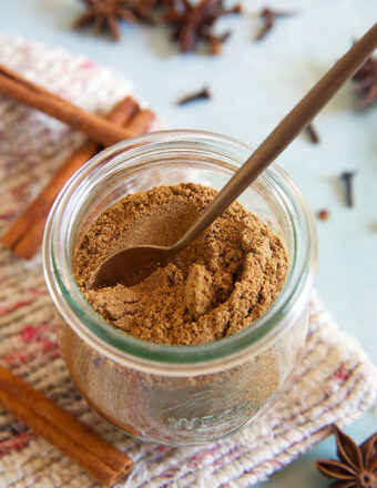 A small spoon is place in a jar of chai spice.