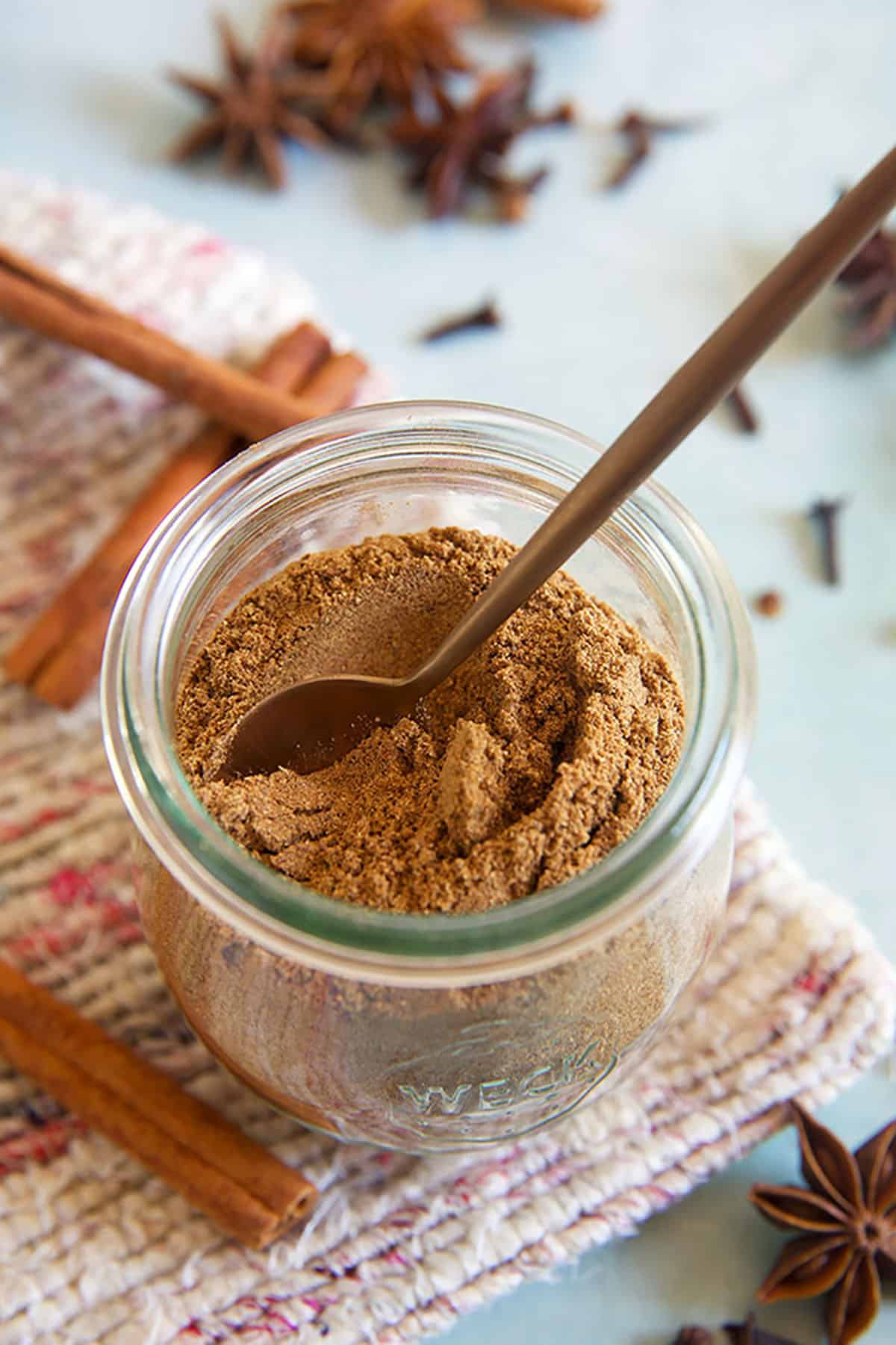 A small spoon is place in a jar of chai spice. 