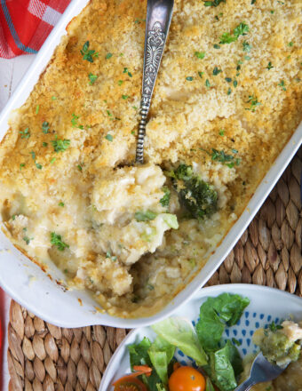 Chicken Divan Casserole in a white baking dish with a spoon in it.