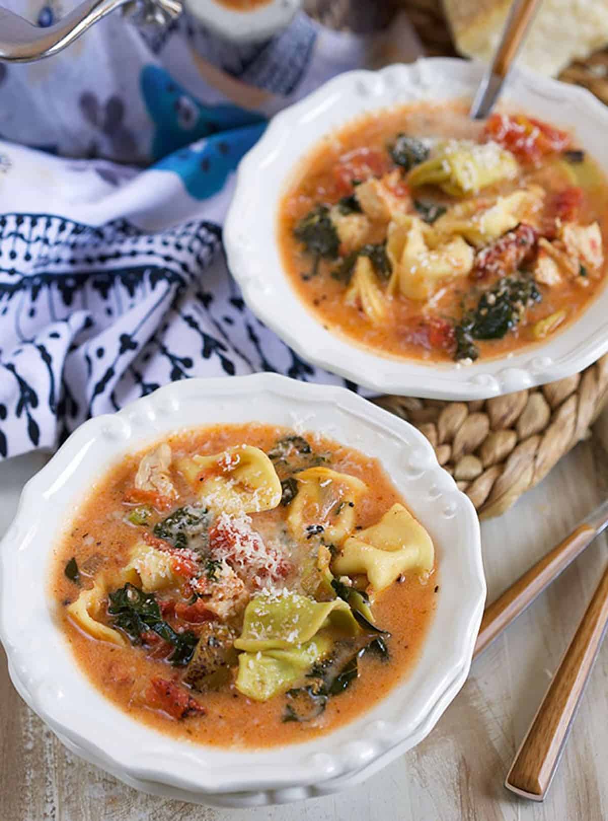 two white bowls with chicken tortellini soup in them.