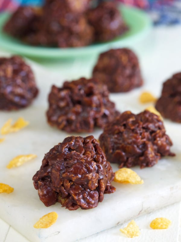 Several pieces of chooclate cornflake candy are placed on a white cutting board.