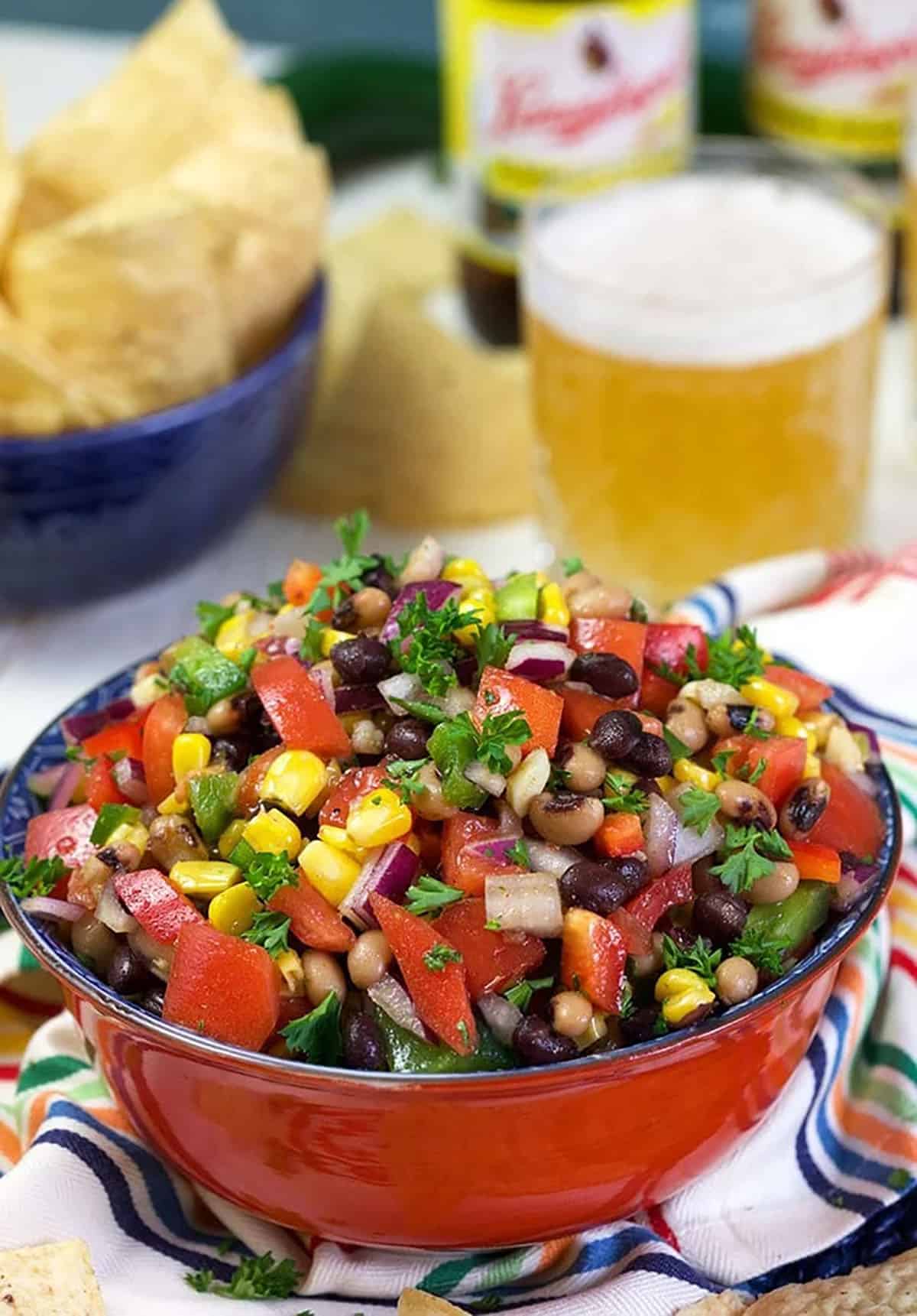 Texas caviar in a red bowl with jalapeños in the background.