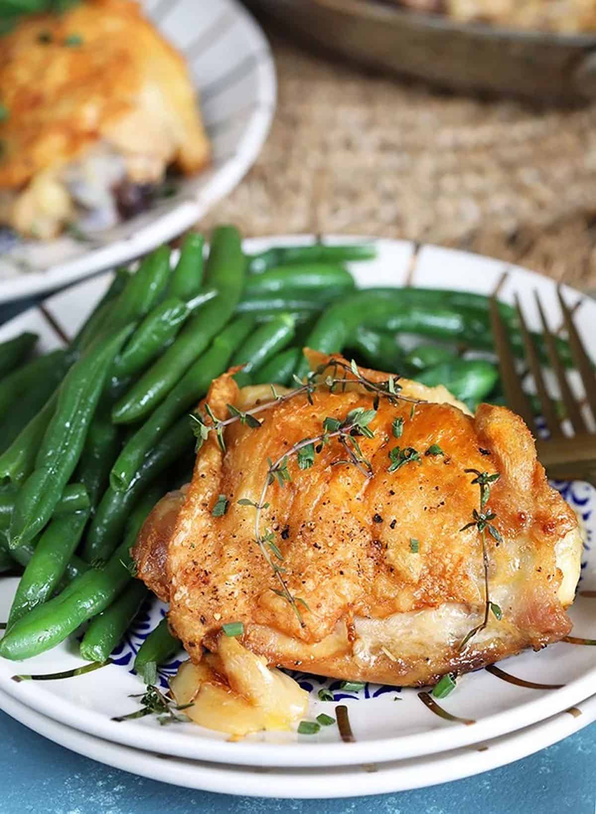 Crispy Baked Chicken Thighs on a white plate with green beans