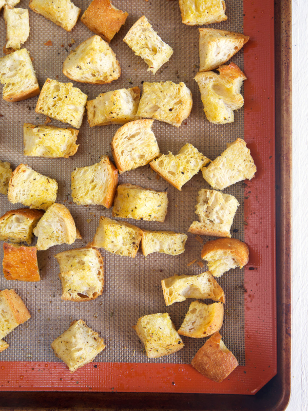 Homemade croutons are baked on a prepared baking sheet.