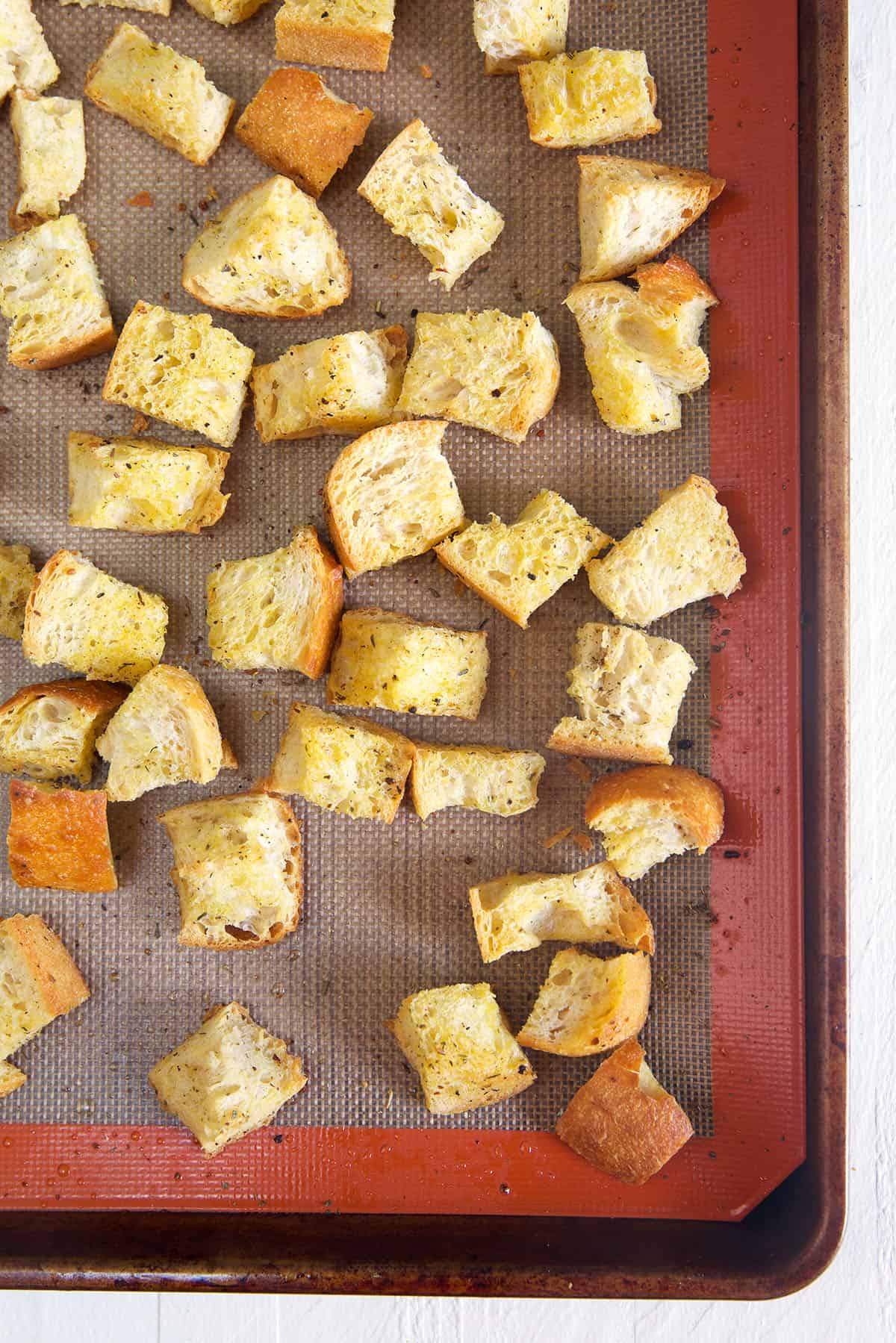 Homemade croutons are baked on a prepared baking sheet.
