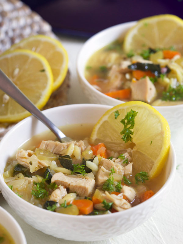 A full bowl of soup is garnished and a spoon is placed in the bowl.