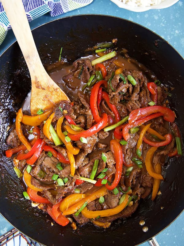 Overhead shot of Mongolian Beef Stir Fry in a wok with a wooden spatula.