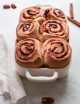 A white pan is filled with baked cinnamon rolls.
