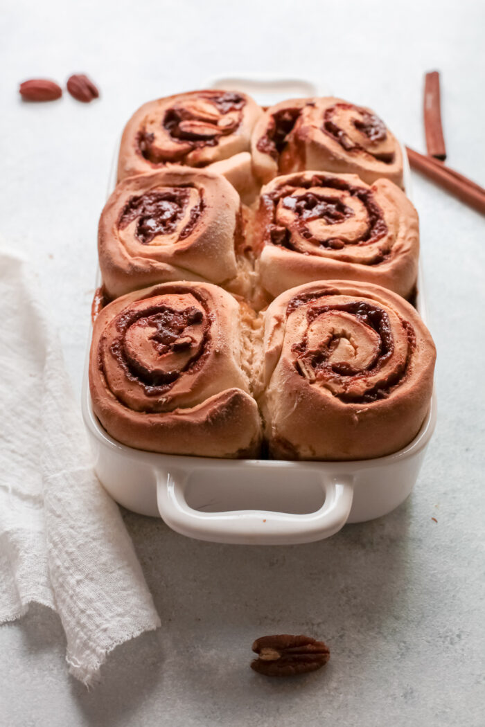A white pan is filled with baked cinnamon rolls. 