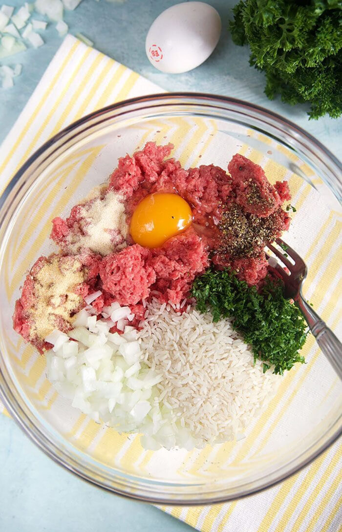 Ingredients for porcupine meatballs in a glass bowl.