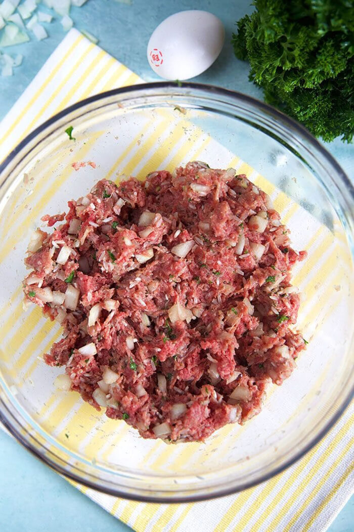 ingredients for porcupine meatballs in a glass bowl ready to be rolled into meatballs.