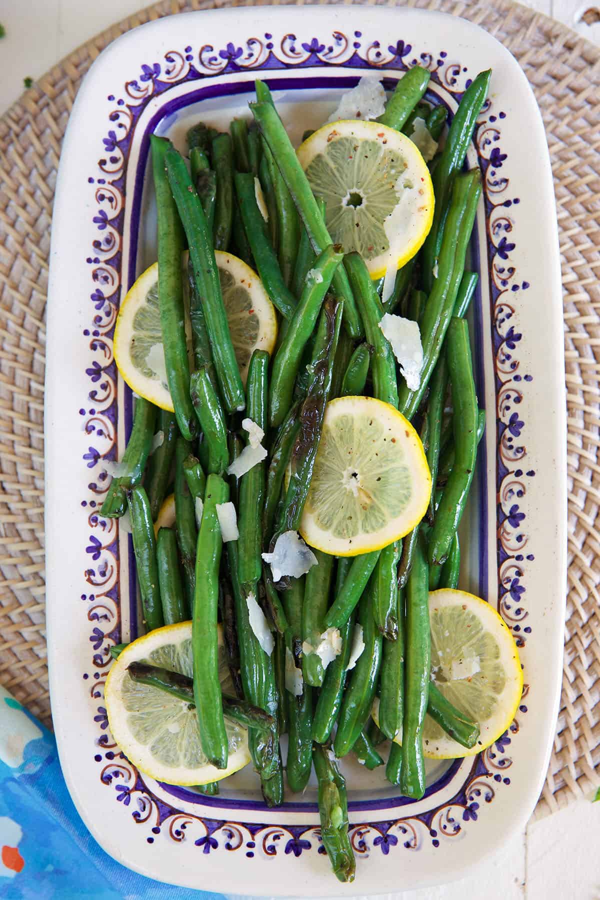 Green beans are plated with parmesan and lemon slices.