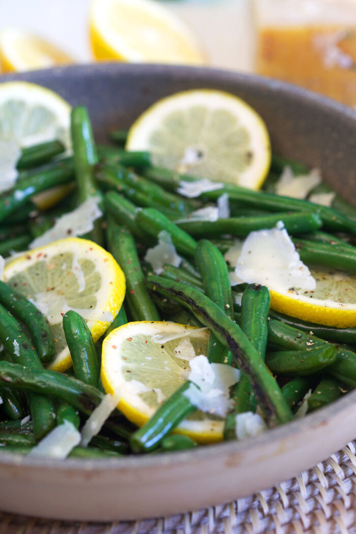 Cheese, lemon slices, and green beans are in a gray pan.