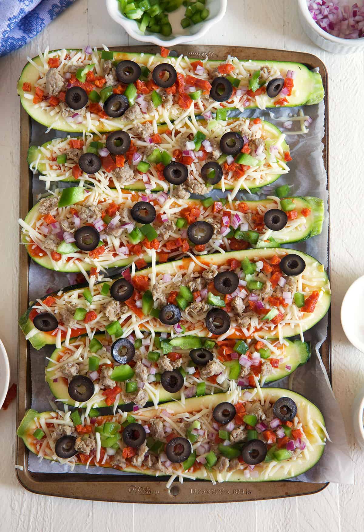 Several zucchini boats are topped with various toppings. 
