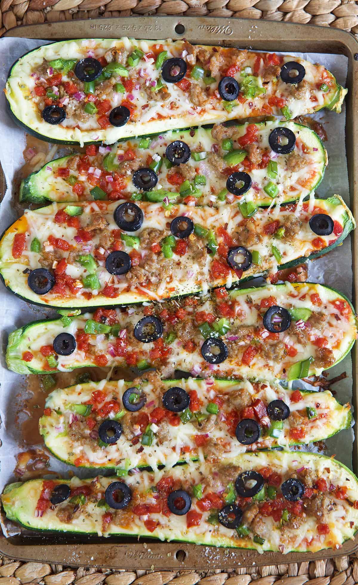 Multiple zucchini boats are placed on a baking sheet, and they're fully cooked.