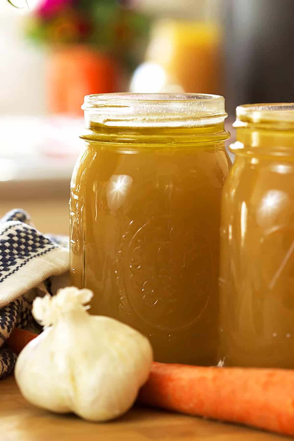 Homemade Beef Stock in a ball canning jar with a bulb of garlic in front of it.